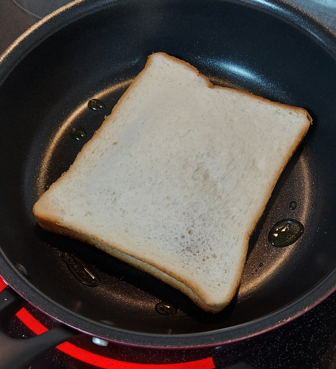 フライパンでカレーを挟んだ食パンを焼いている写真